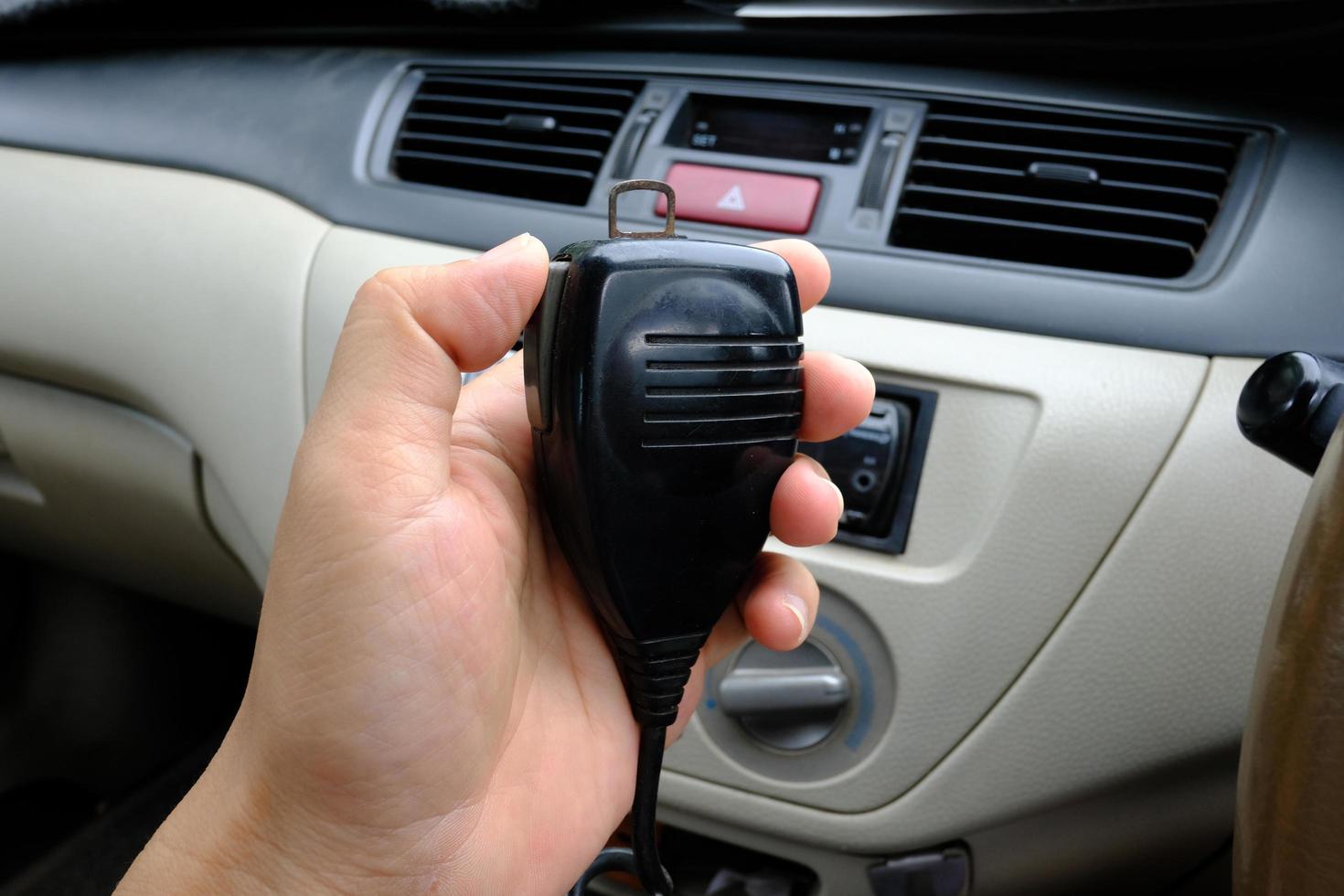 Hand holding microphone walkie-talkie radio communication in car photo