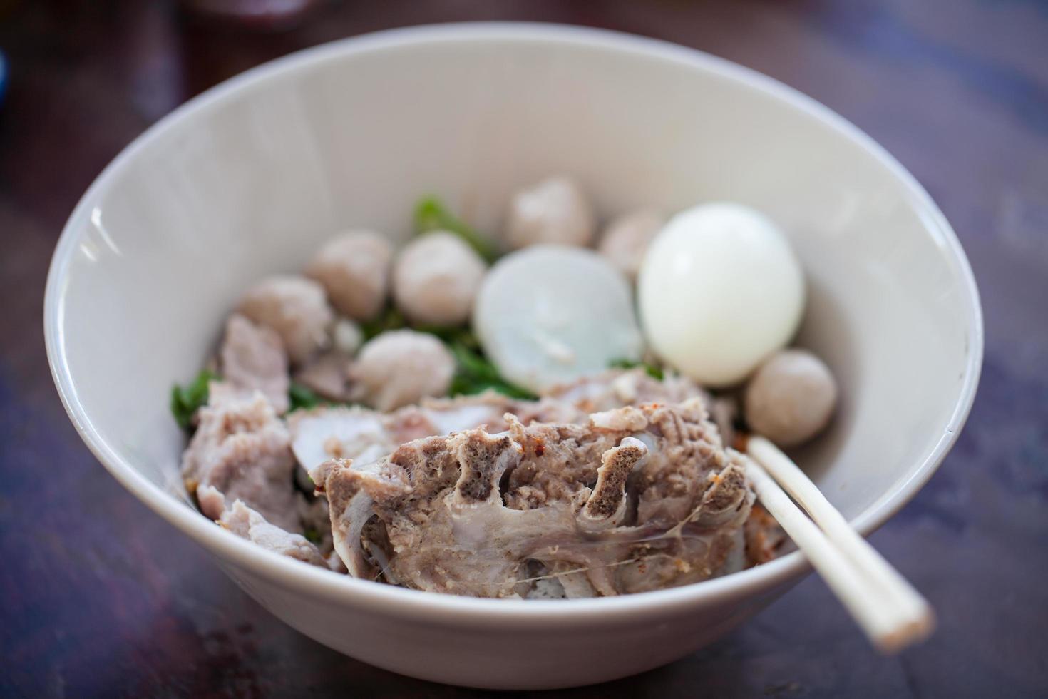 Thai noodles with  pork and Pork meatballs in white disk photo