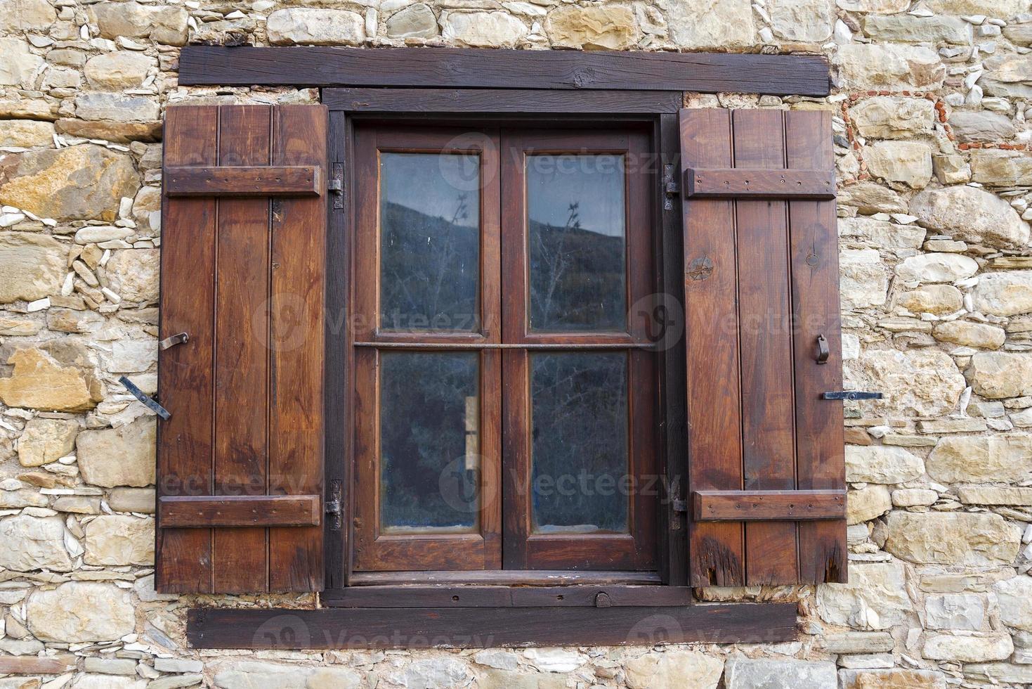 An old window with wooden shutters in a stone house. photo