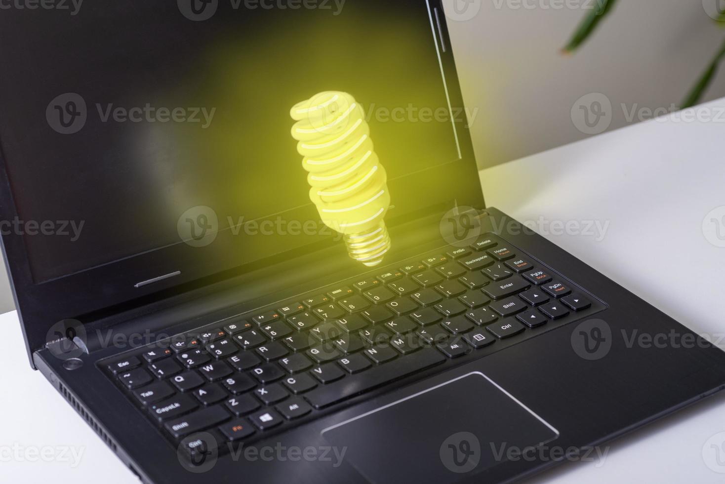 Computer on desktop in office with bulb icon hologram. Multi exposure. Concept of idea. photo