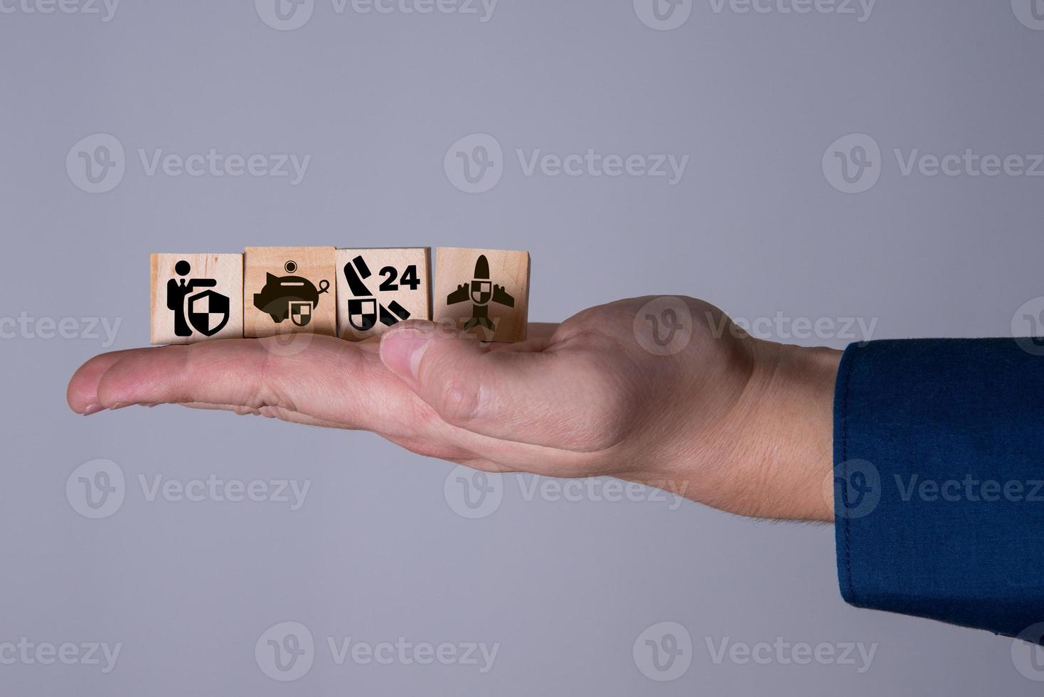 The hand holds wooden cubes with insurance icons. photo