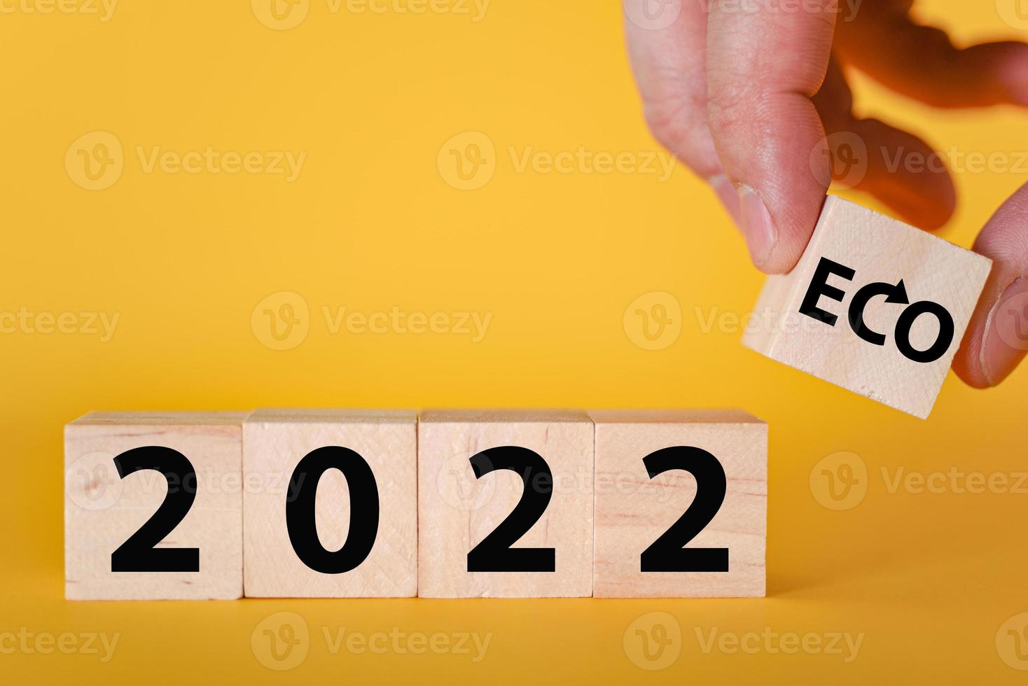 A hand holds wooden cubic blocks on a yellow background of 2022. The ecological year is 2022. photo
