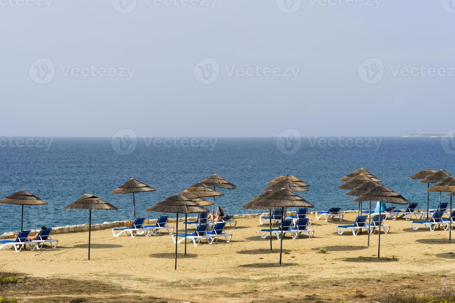 Beach sunbeds and parasols overlooking turquoise water photo