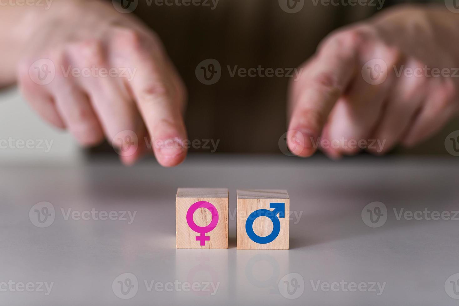 A choice between a man and a woman. the hands point to two wooden cubes with a gender icon, a male and a female sign. photo
