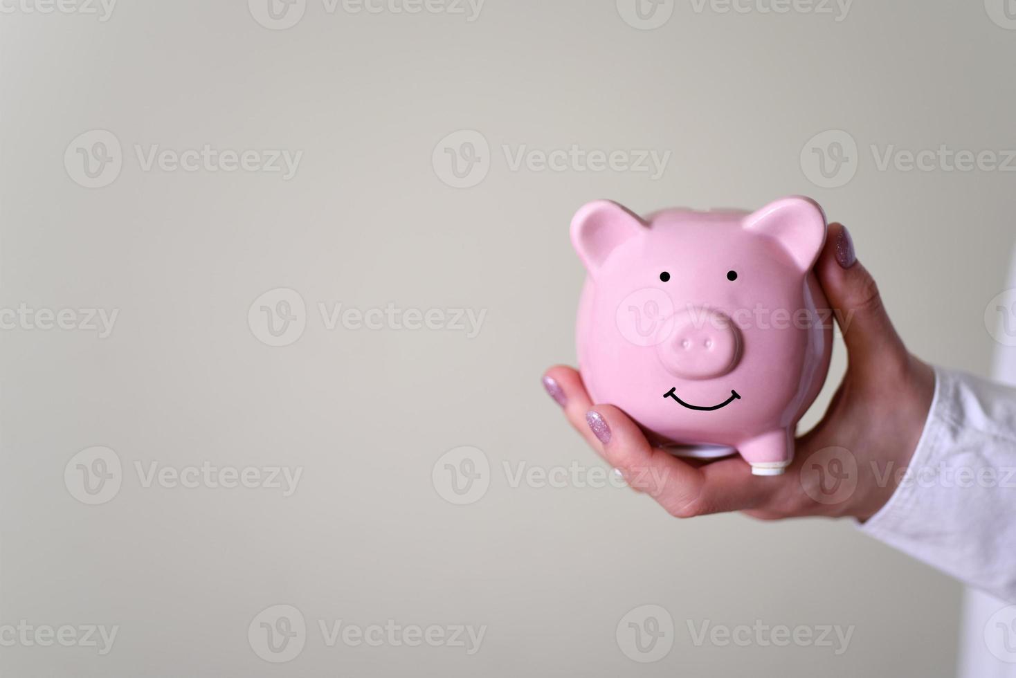 The hand holds a piggy bank in the form of a pig. photo