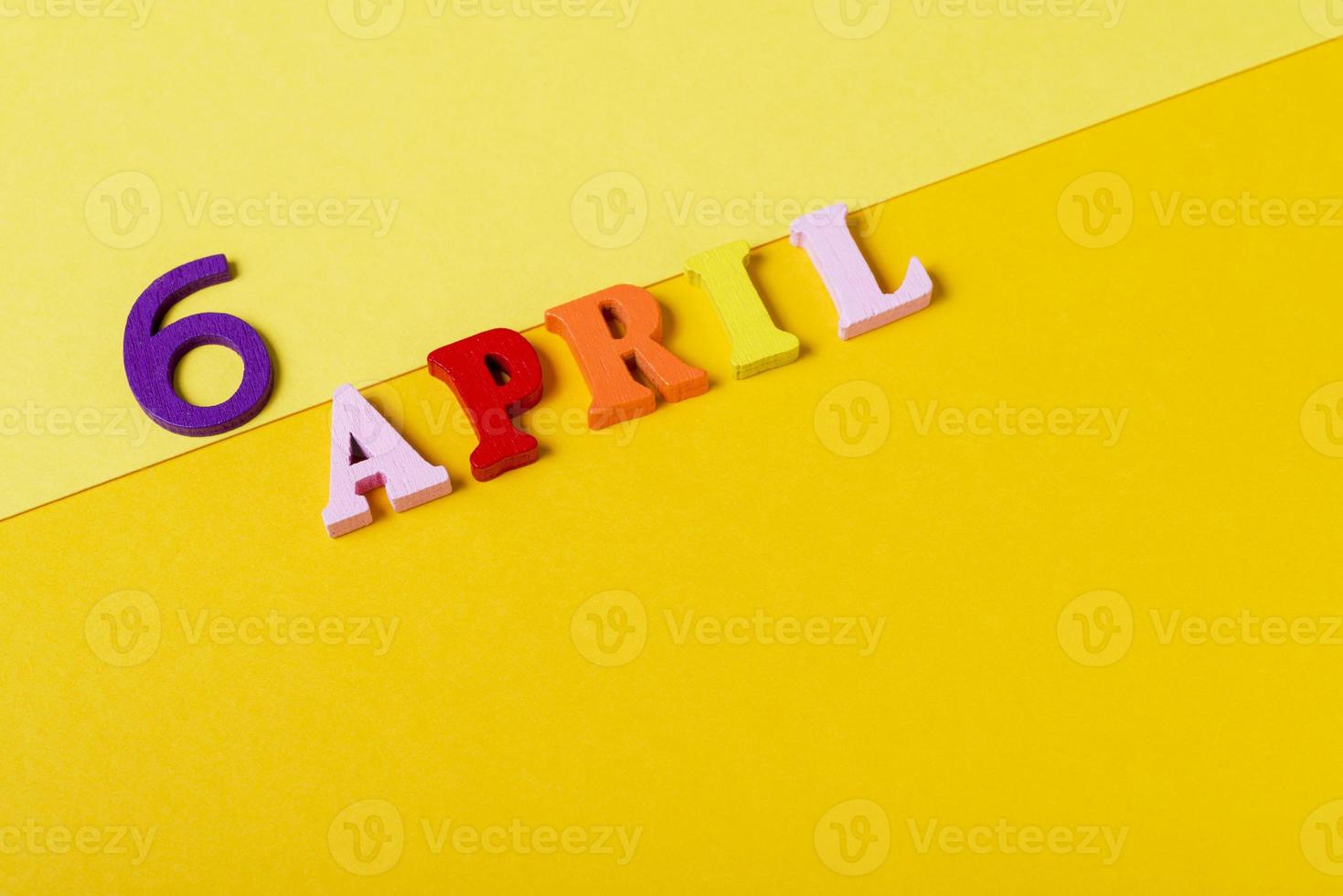 Wooden letters of the sixth of April on a yellow background. photo