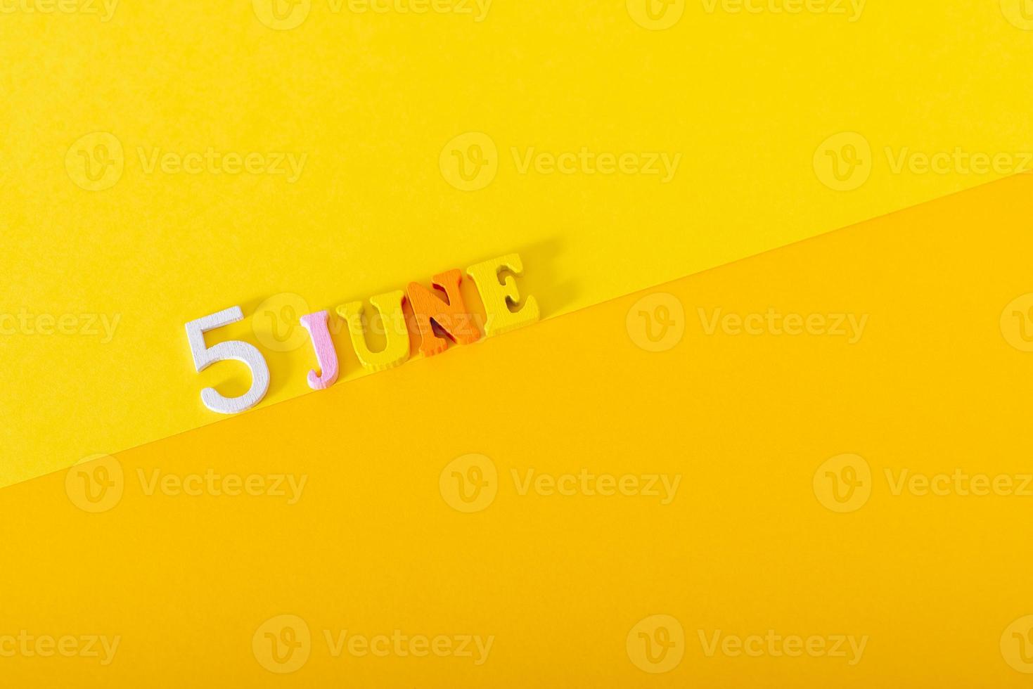 5 de junio, día mundial del medio ambiente. letras y números de madera sobre un fondo amarillo. foto