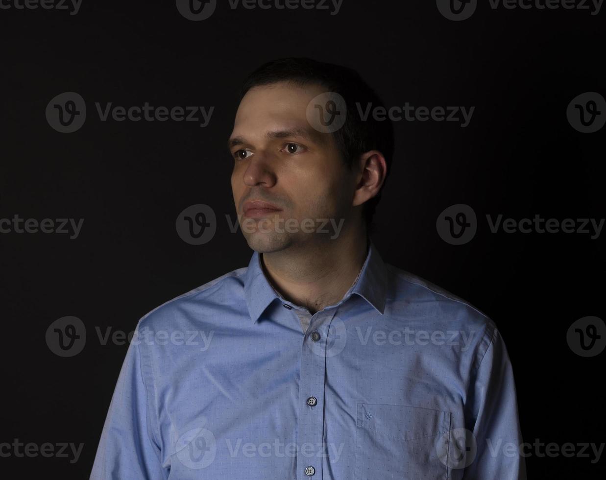 A man in a blue shirt on a black background. photo