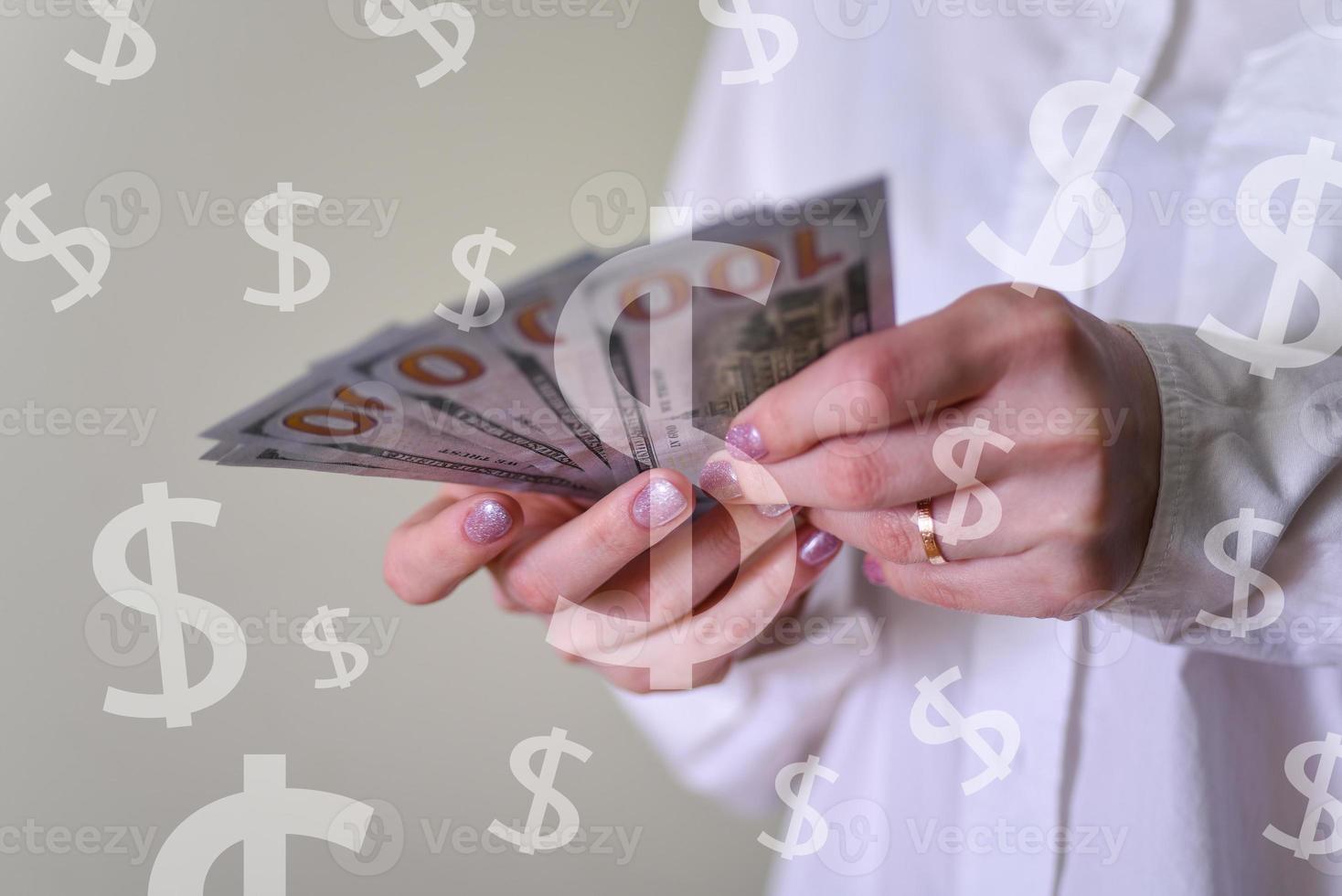 dólares de papel moneda en la mano de una mujer de cerca, calculando las finanzas foto