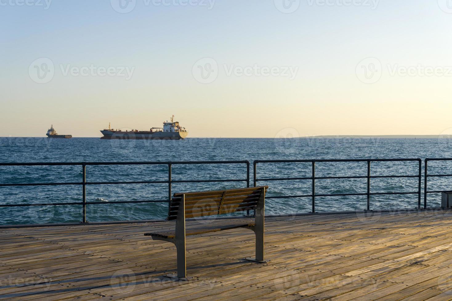 Banco sobre tarima de madera con vistas al mar. foto