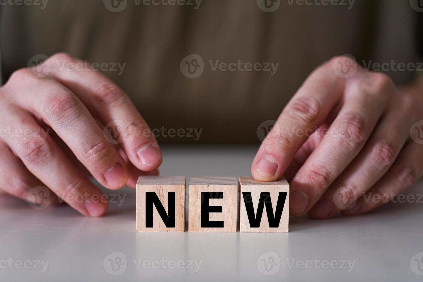 Businessman holding wooden cubes with new word. photo