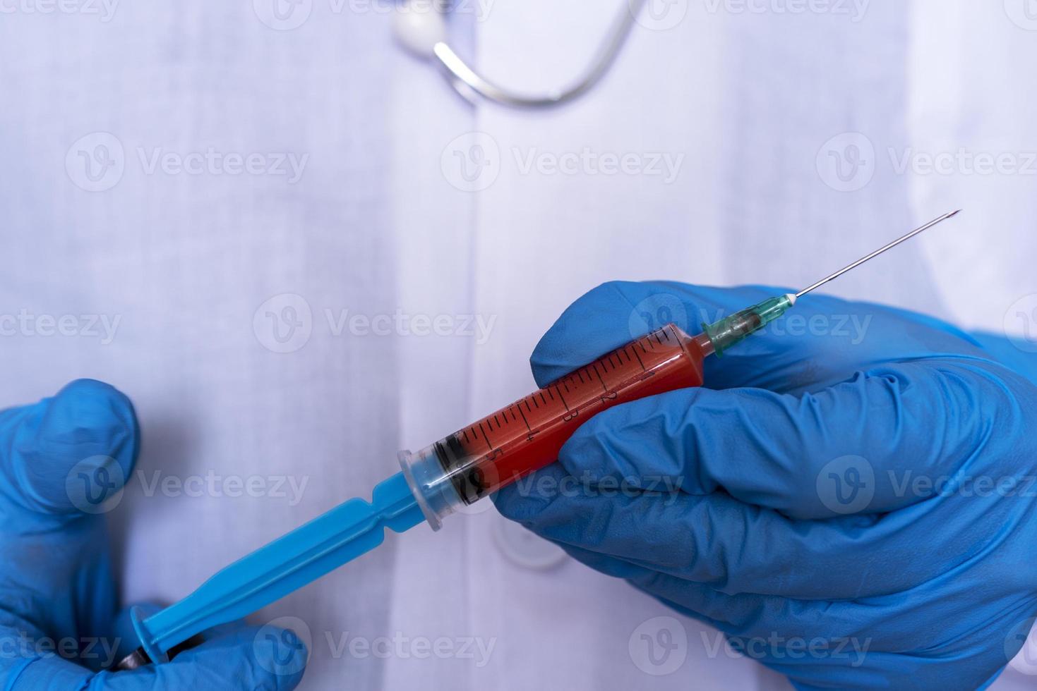 The doctor's hands in medical gloves hold a syringe with blood. photo