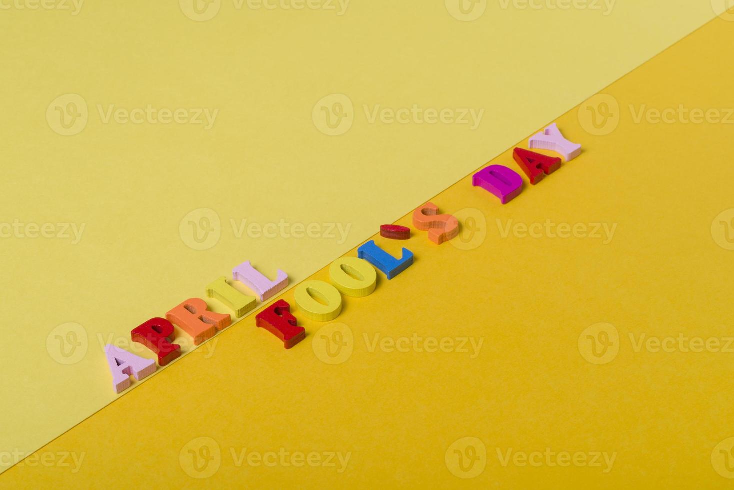 Wooden letters the first of April on a yellow background. The concept of the holiday, photo