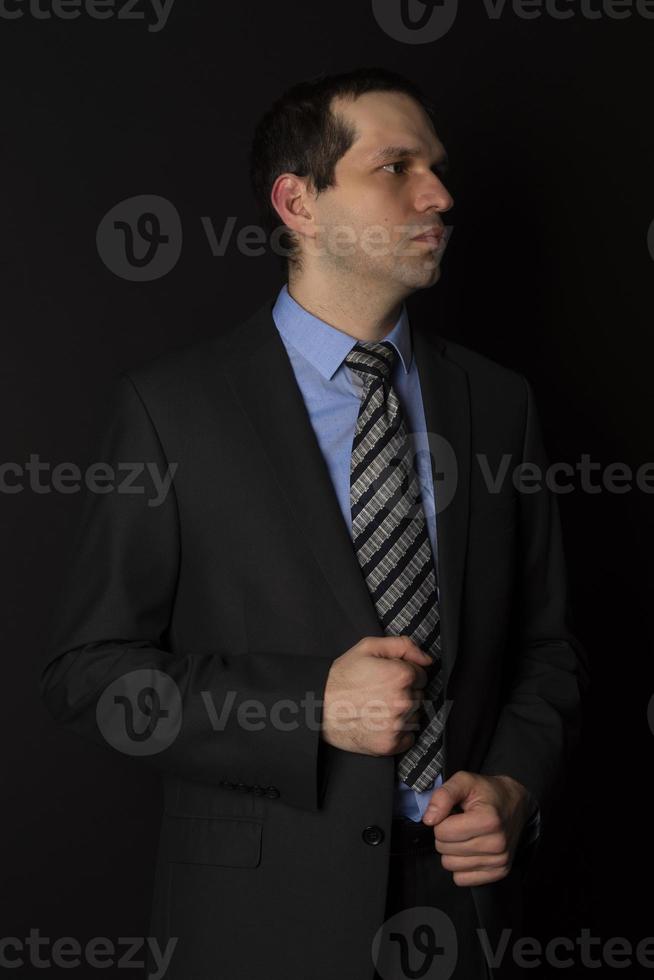 un hombre con un traje negro sobre un fondo negro. foto