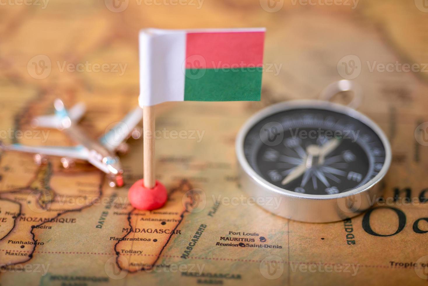 Flag of Madagascar, compass and airplane on the world map. photo