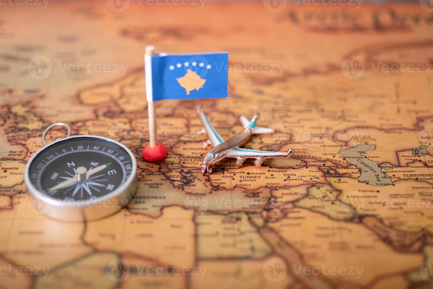 bandera de la república de kosovo, brújula y avión en el mapa mundial. foto