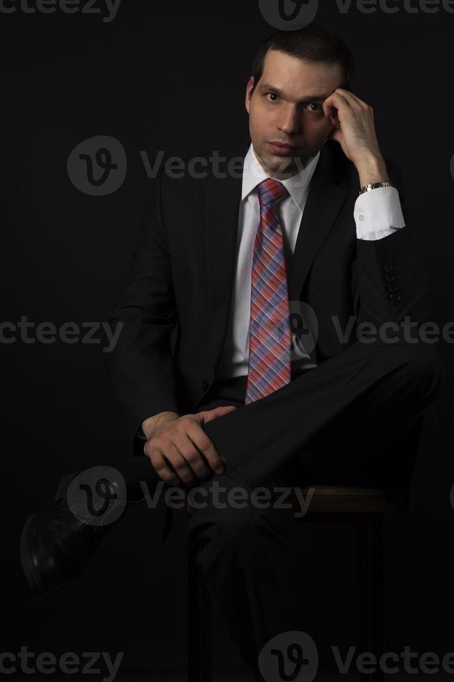 A man in a black suit on a black background. photo