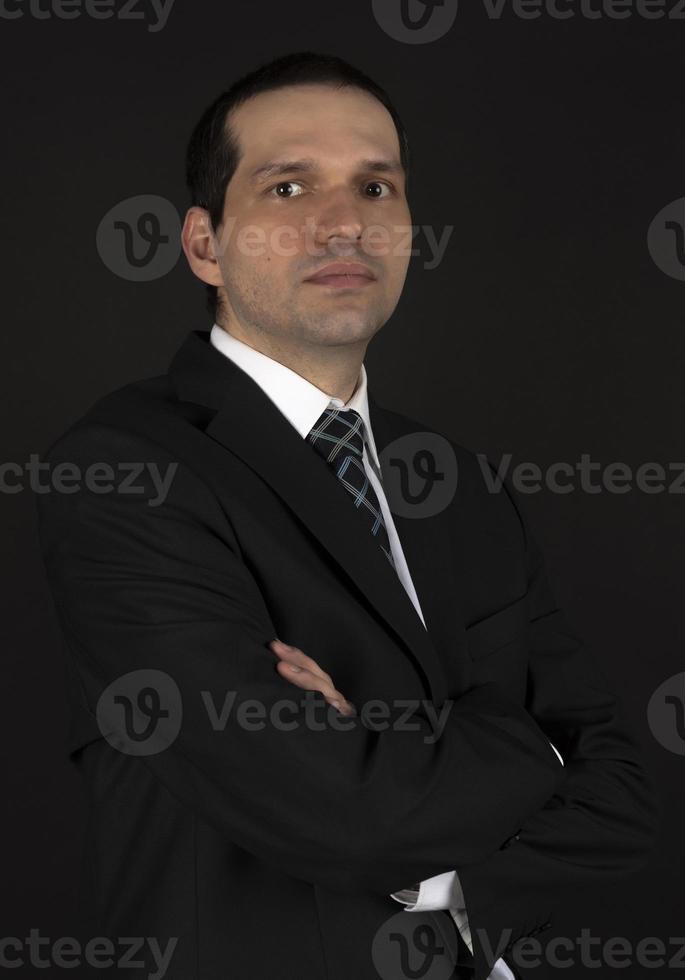 A man in a black suit on a black background. photo