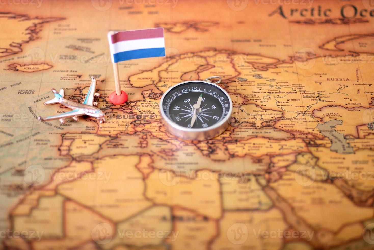 Flag of the Netherlands, compass and airplane on the world map. photo