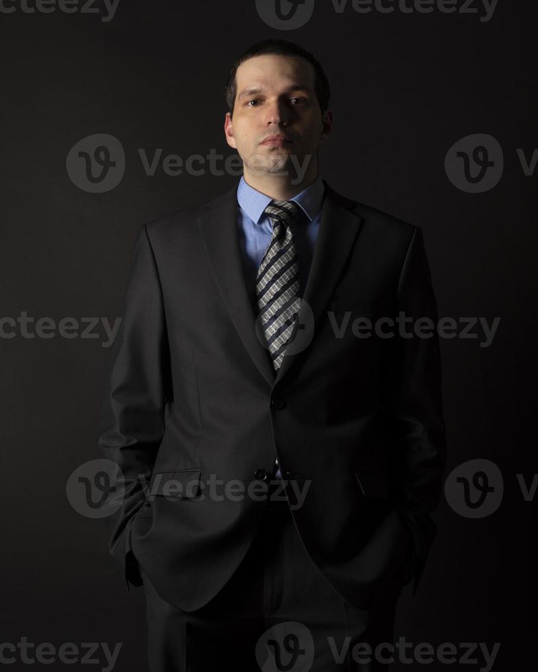 A man in a black suit on a black background. photo