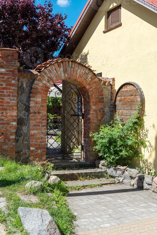 arco de ladrillo con reja de forja, entrada en el patio de la casa. foto