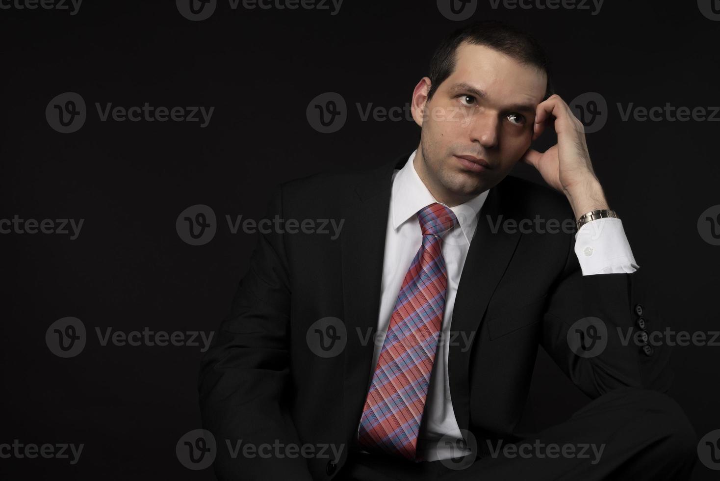 A man in a black suit on a black background. photo