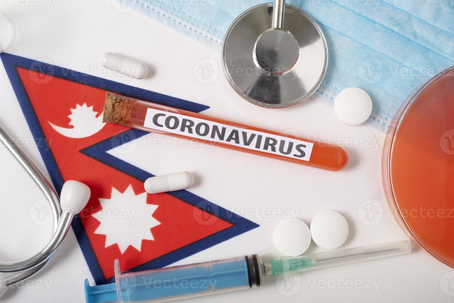 Coronavirus, nCoV concept. Top view protective breathing mask, stethoscope, syringe, tablets on the flag of Nepal. photo