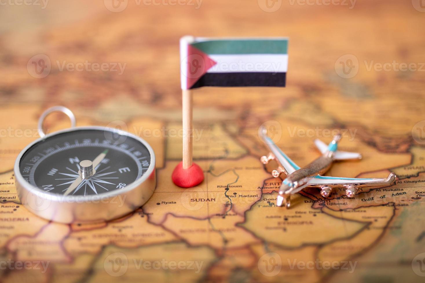 Flag of Sudan, plane and compass on the world map. photo