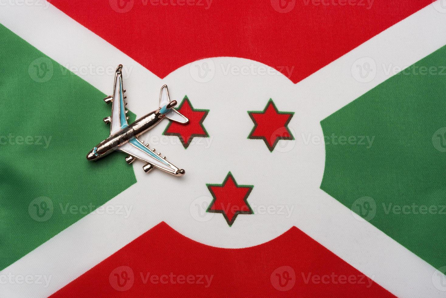 avión sobre la bandera del concepto de viaje de burundi. avión de juguete en una bandera. foto