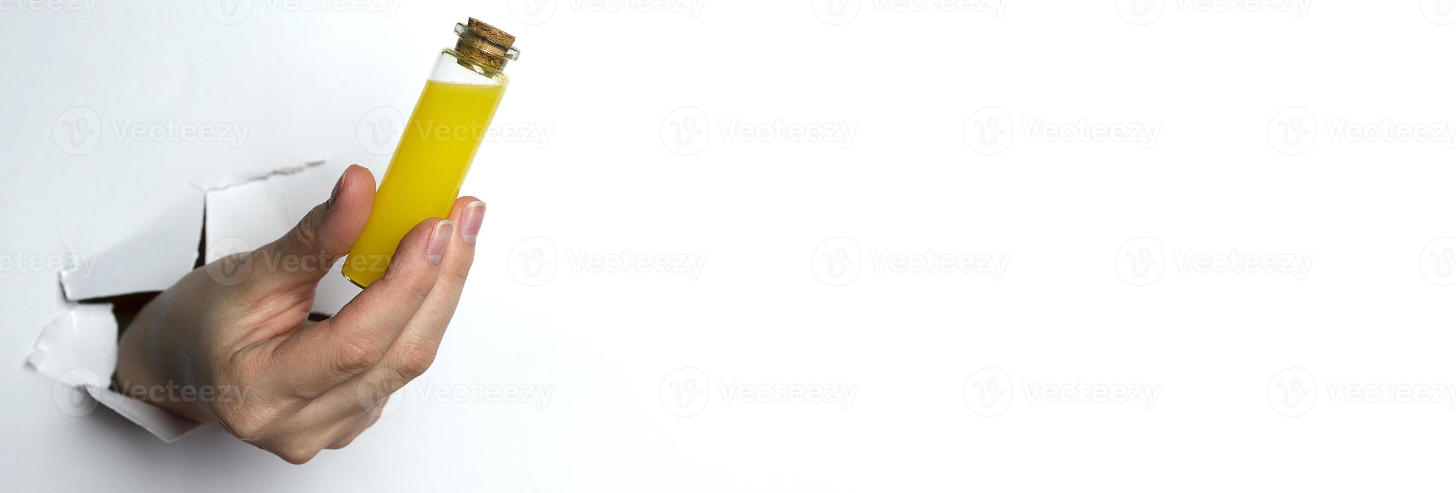 Female hand holding a test tube with yellow liquid on a white background. Copy Space. photo