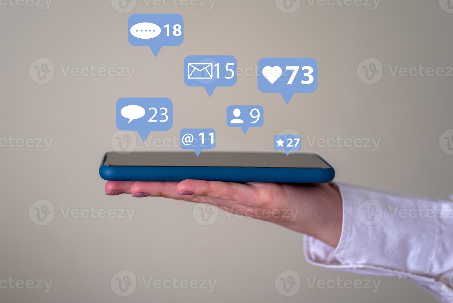 The concept of a communication network. A woman's hand holds a phone with pop-up notification icons. photo