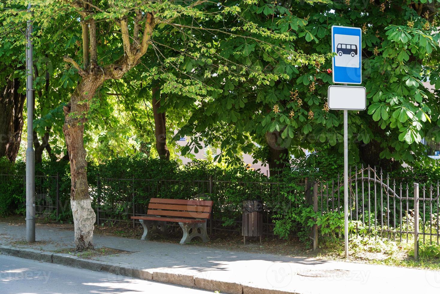 A bench near the bus stop with trees. photo
