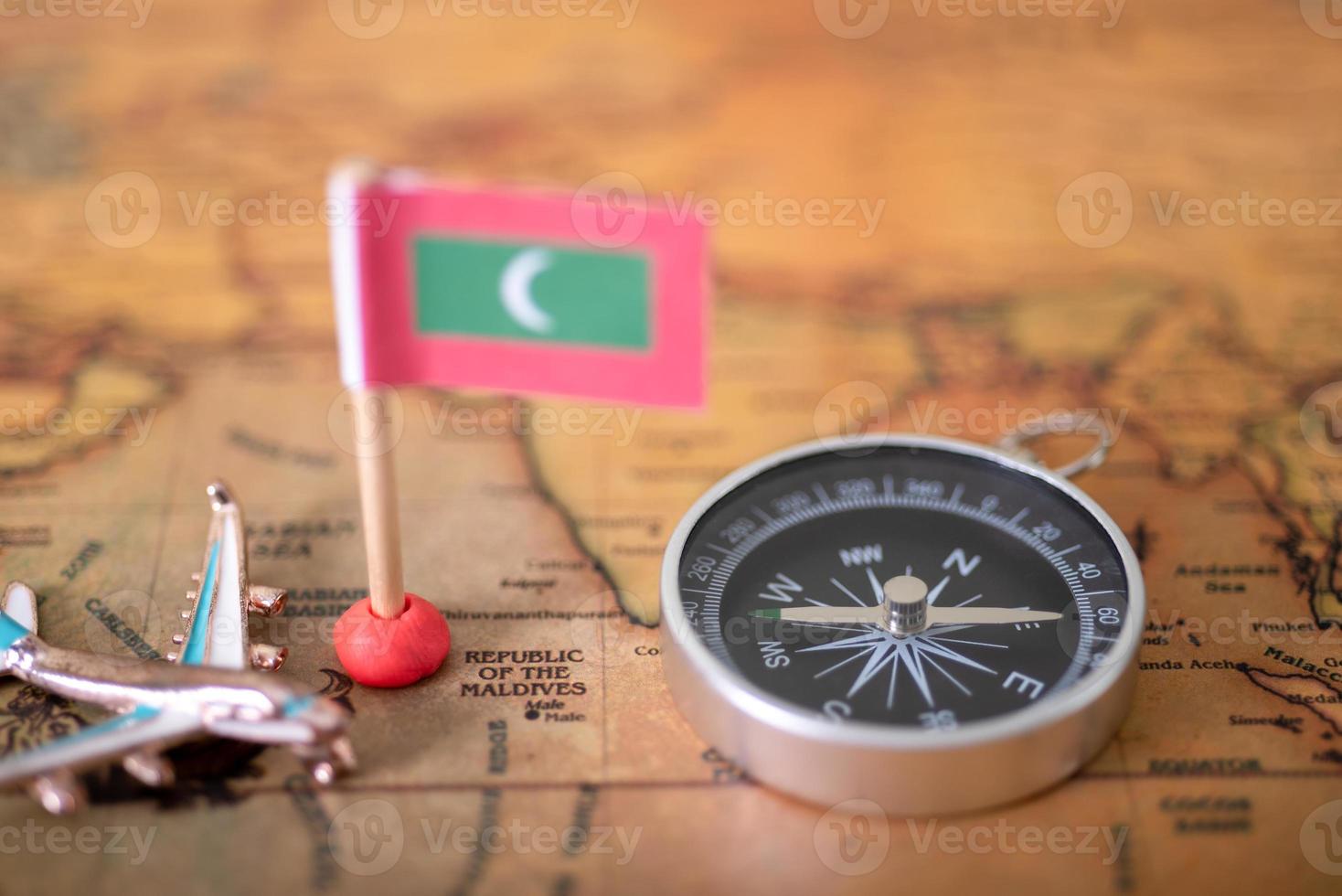 bandera de maldivas, avión y mapa mundial de brújula. foto