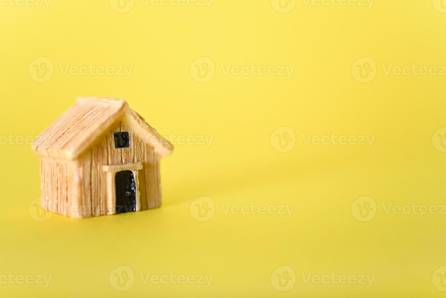 A small toy house on a yellow background. photo