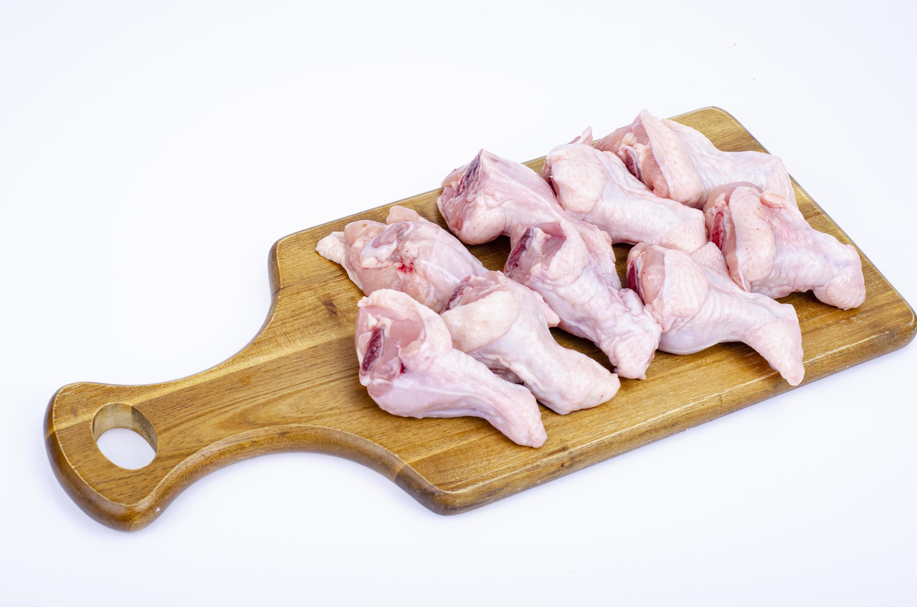 alitas de pollo crudas con hueso y piel en tabla de cortar de madera