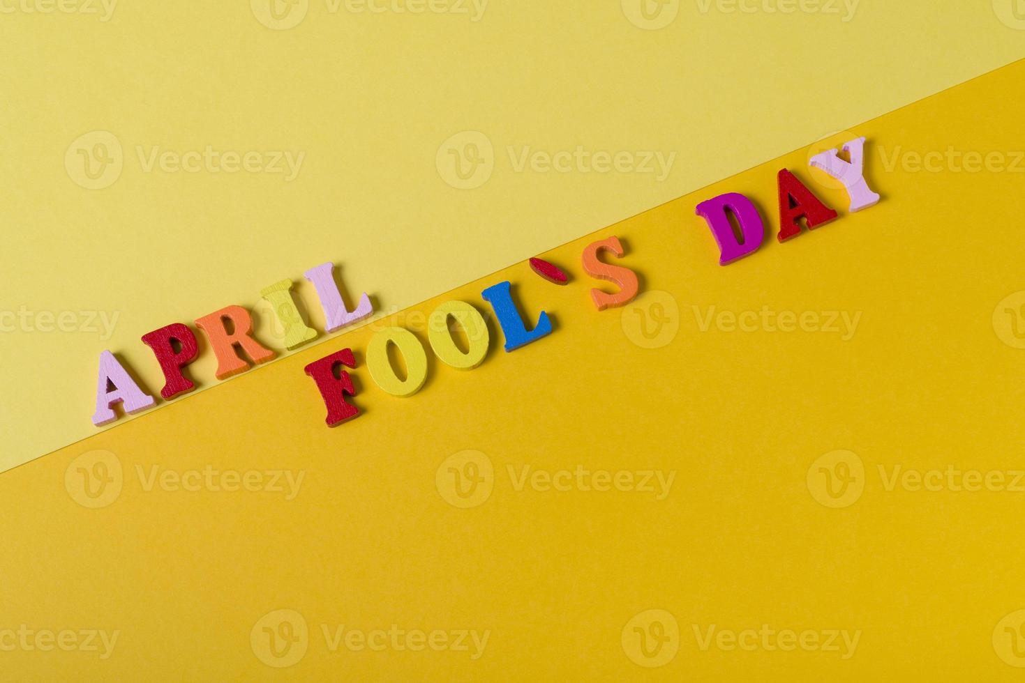 Wooden letters the first of April on a yellow background. The concept of the holiday, photo