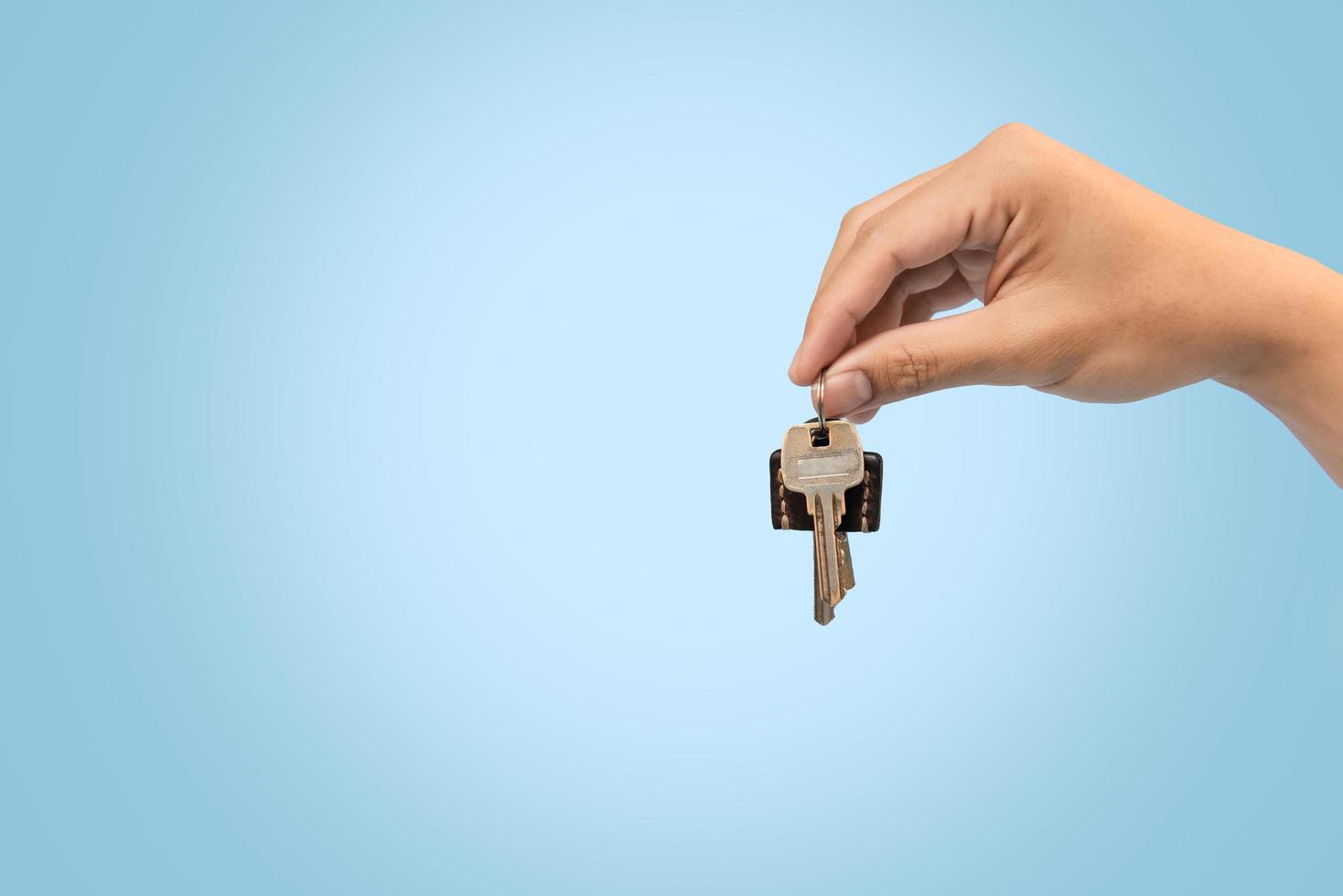 Hand holding keys blue background for refinance plan and real estate concept. photo