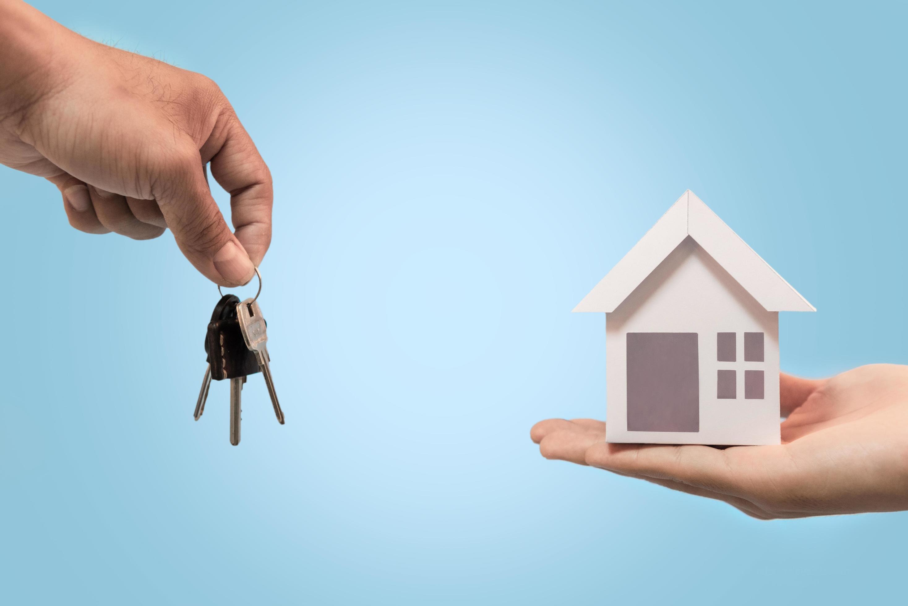 Businessman giving house keys and house model to customer in blue
