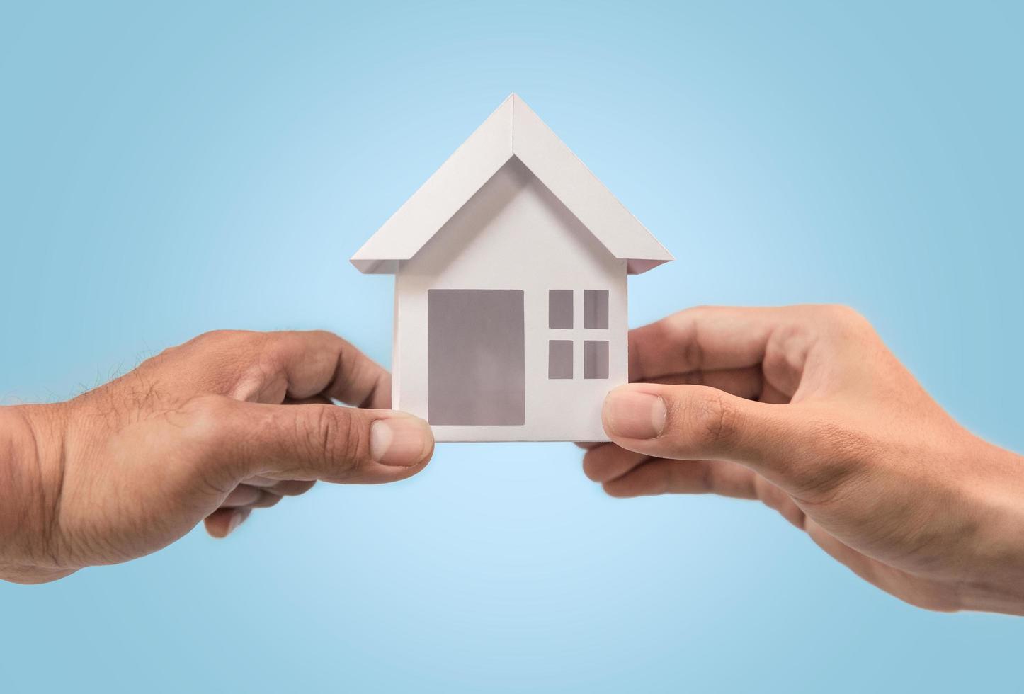 Businessman giving house model to customer in blue background for refinance plan and real estate concept. photo