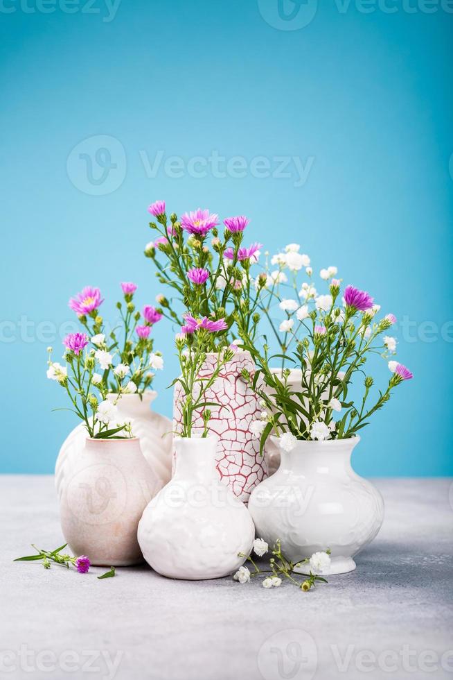 Vases with beautiful flowers on light table photo