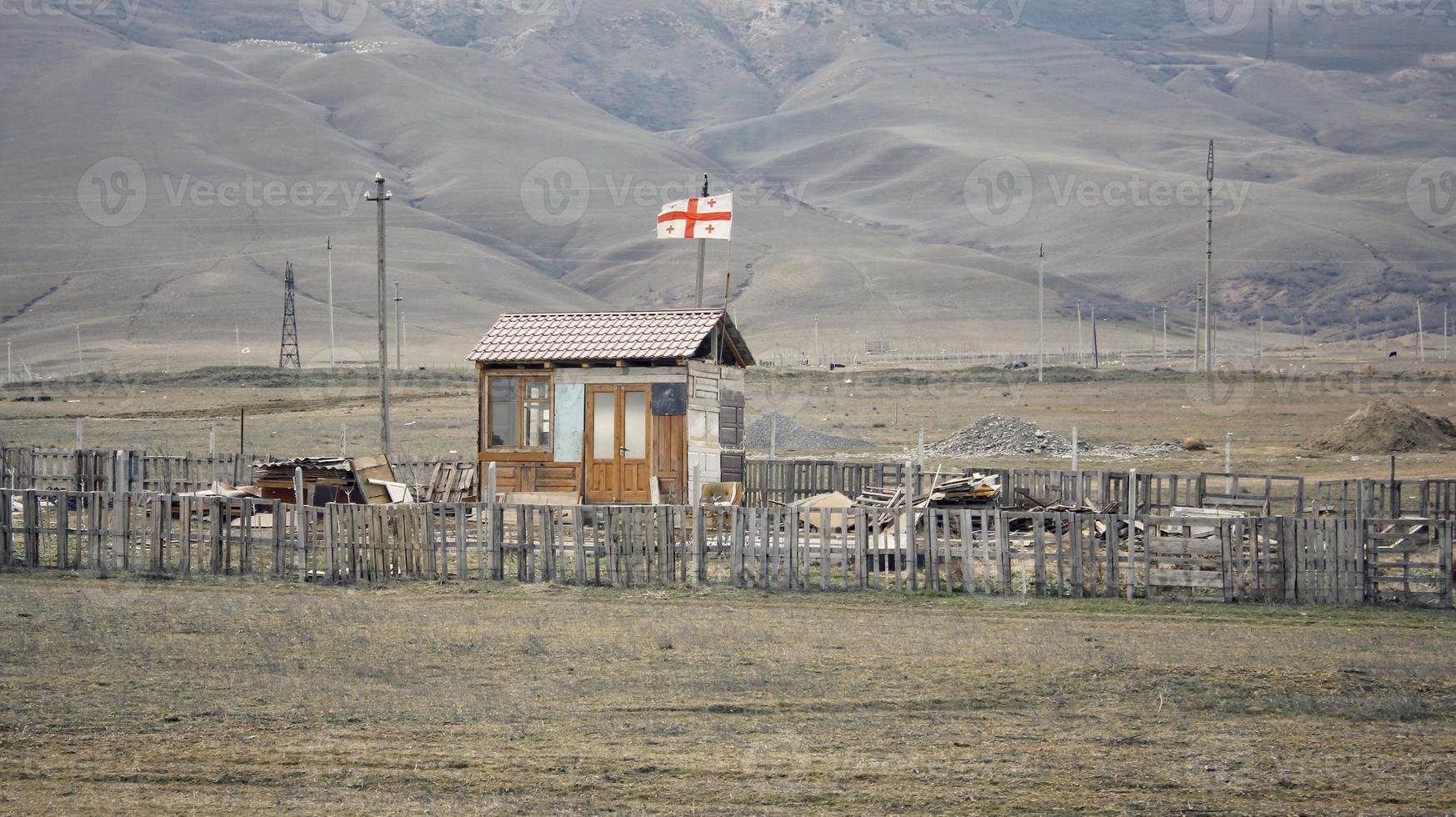 una cabaña de madera solitaria con una bandera nacional georgiana en una zona desierta. foto