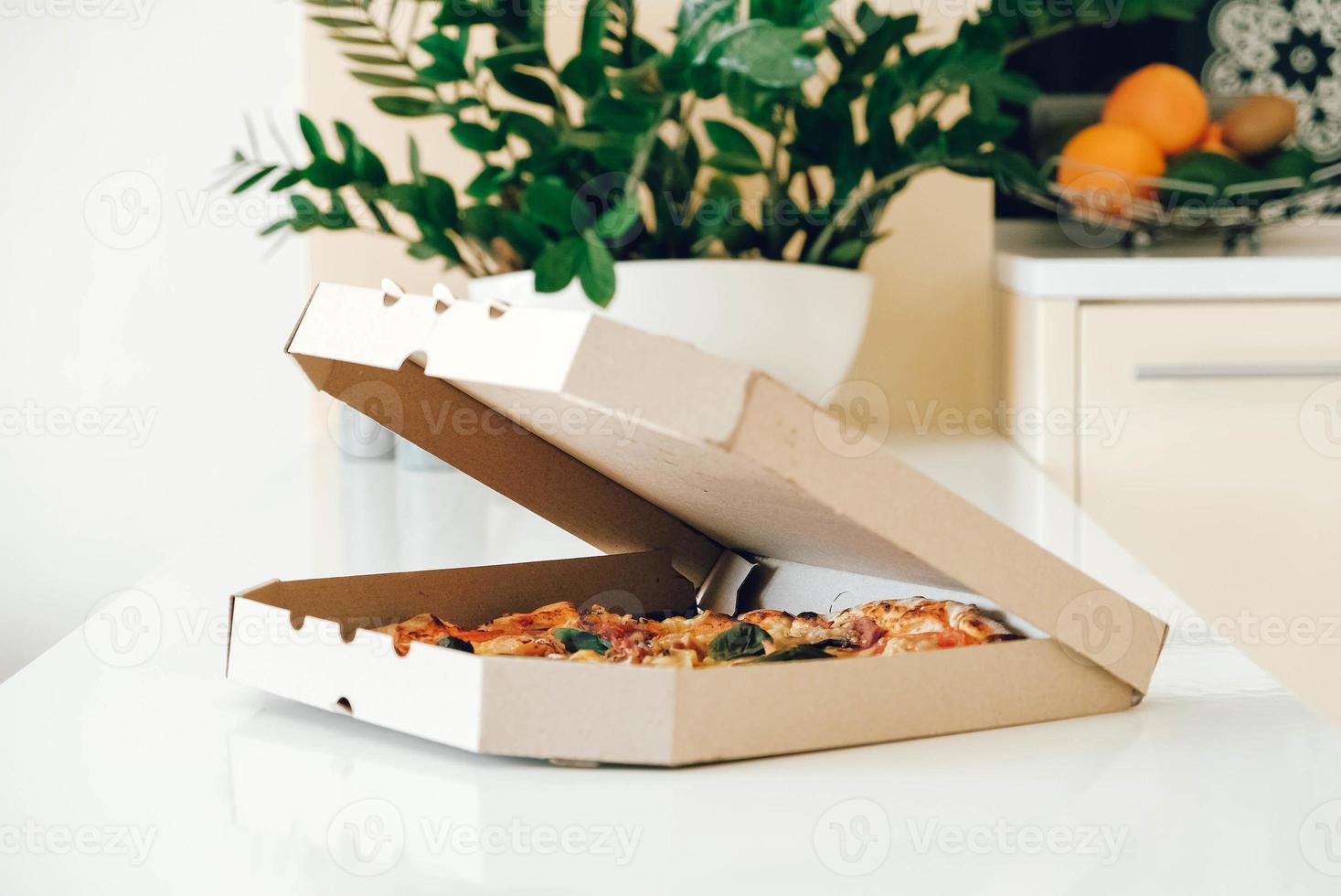 pizza en una caja de cartón sobre un fondo de mesa blanco. copiar, espacio vacío para texto foto