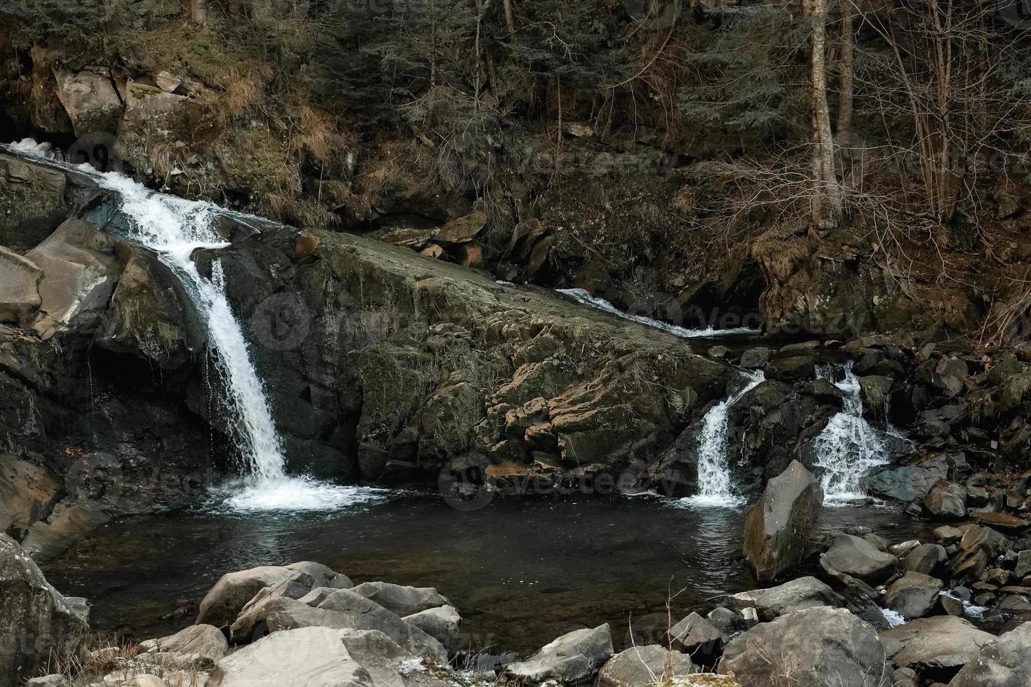 Small cascading waterfall among the rocks and forest. Beautiful mountain landscape. Copy, empty space for text photo