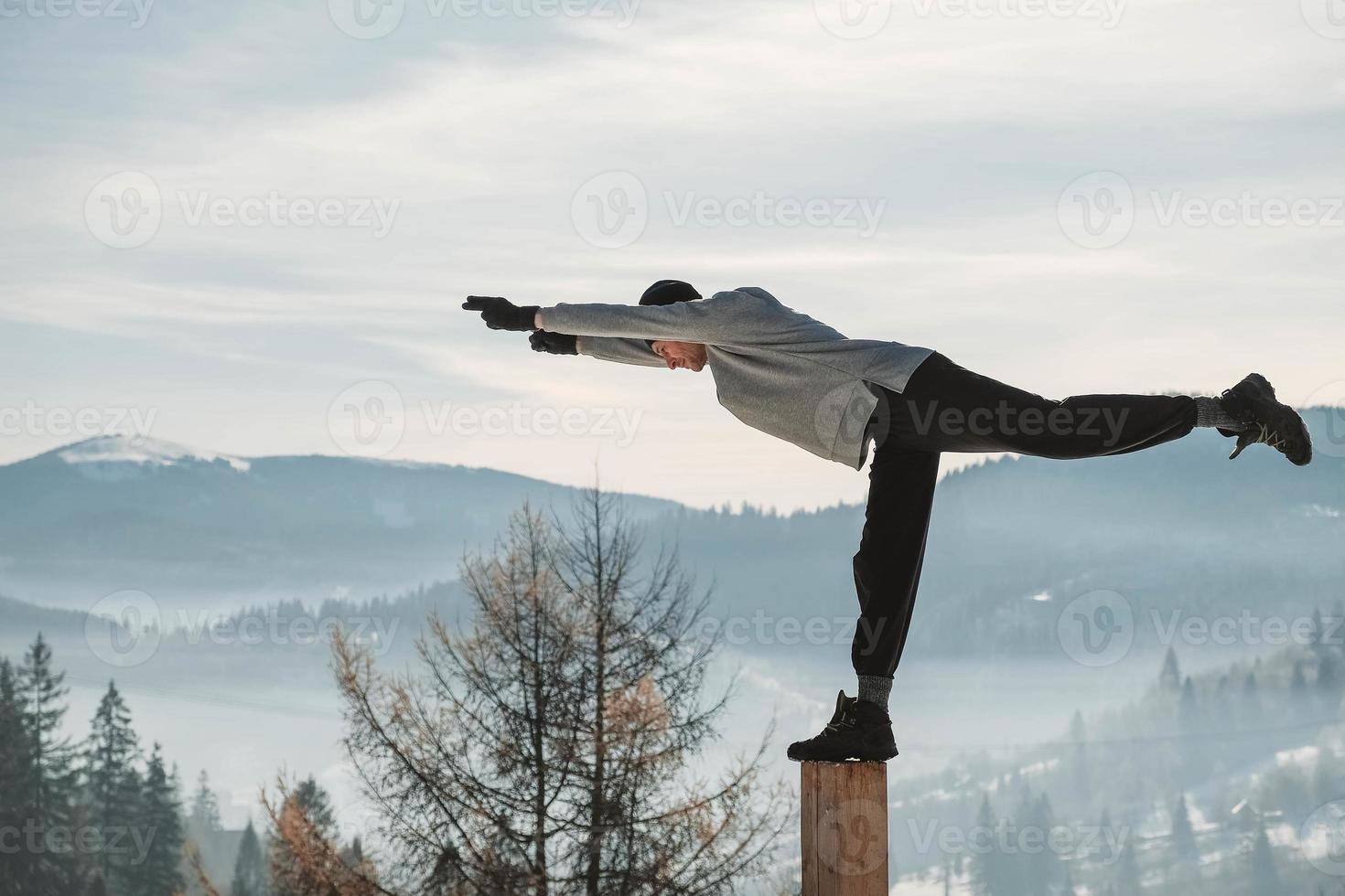 Man practicing yoga and balancing exercises in the winter mountains and enjoying life. Copy, empty space for text photo