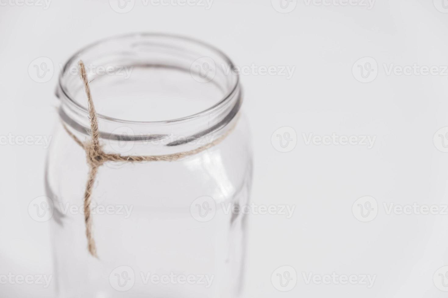 frasco transparente de vidrio sobre un fondo de mesa blanco. copiar, espacio vacío para texto foto