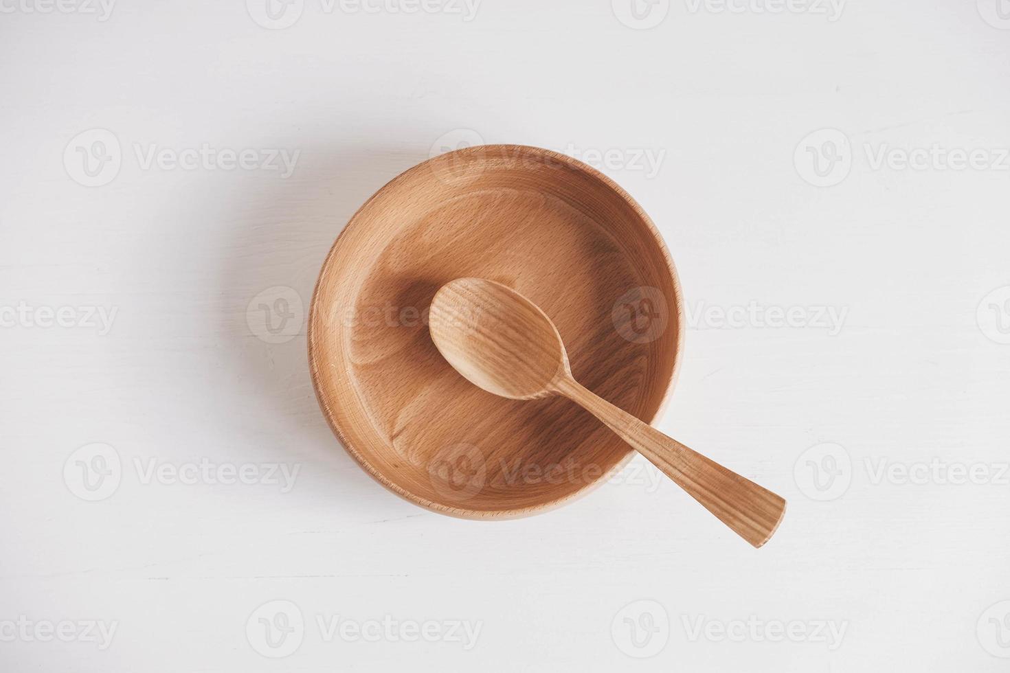 Empty wooden bowl and wooden spoon on a white table background. Top view. Copy, empty space for text photo