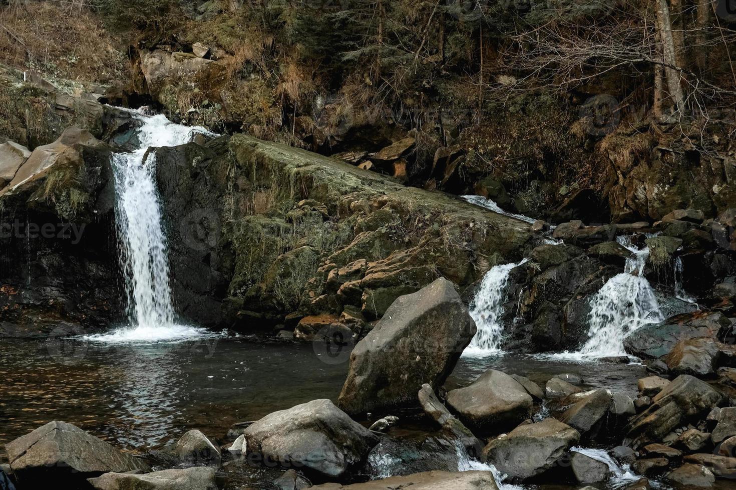 Small cascading waterfall among the rocks and forest. Beautiful mountain landscape. Copy, empty space for text photo