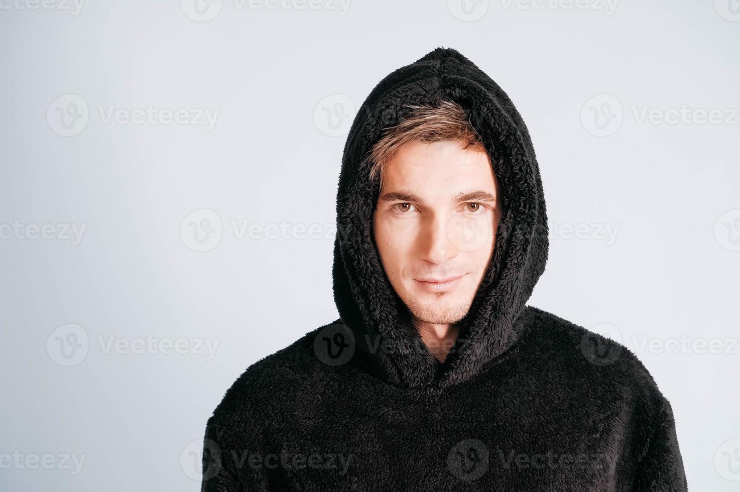 retrato de un joven con sudadera negra con capucha en un fondo blanco. copiar, espacio vacío para texto foto