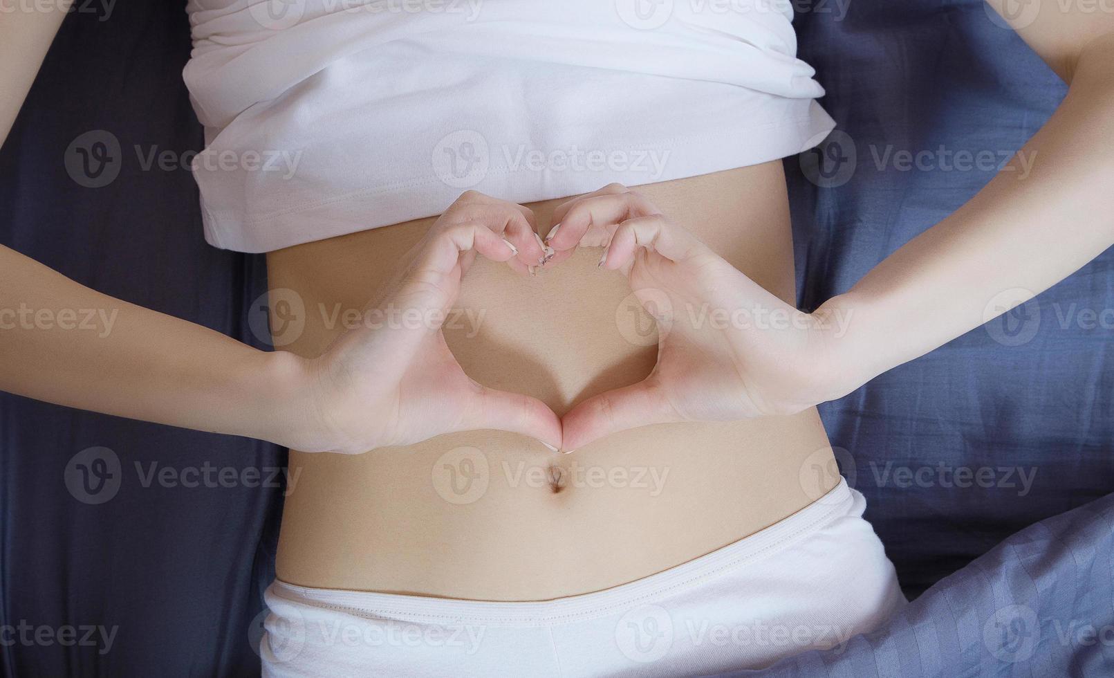 nutrición saludable y concepto de salud abdominal. primer plano del estómago plano de la mujer. chica en la cama con sensación de hambre. vista superior foto