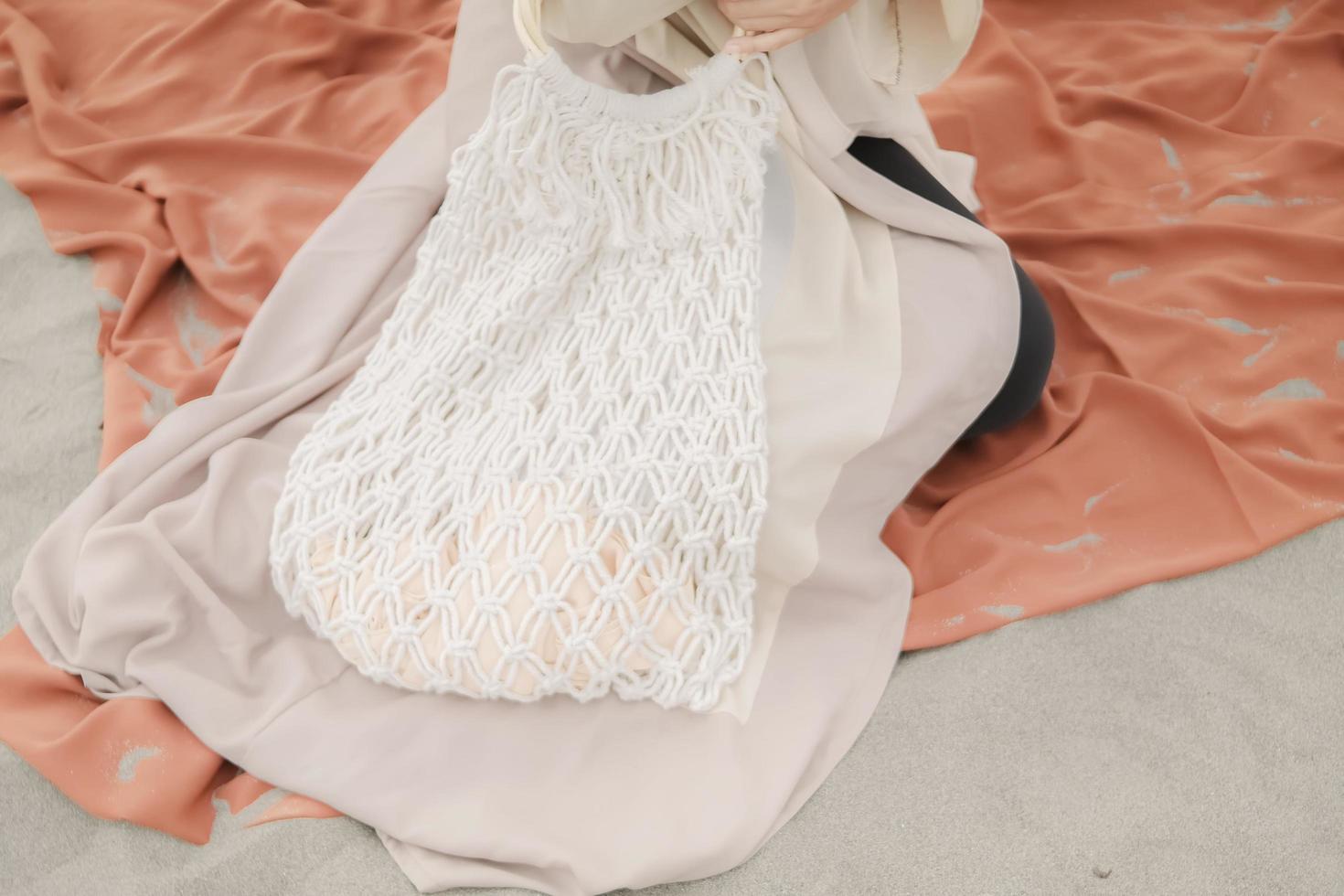 Beautiful islamic female model wearing hijab fashion, a modern wedding dress for muslim woman sitting in the sand and beach. Portrait an asian girl model using hijab having fun at the beach with trees photo